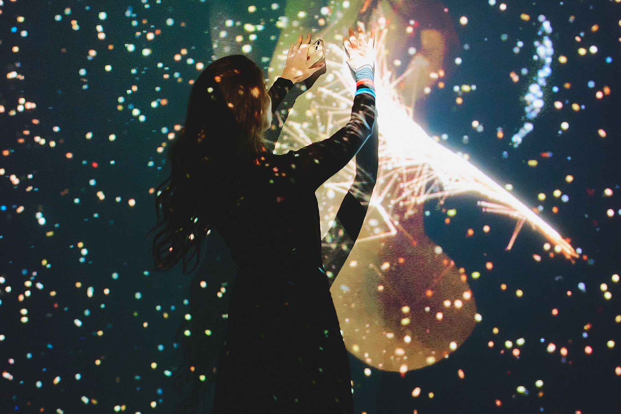 A visitor reaching toward a glowing interactive projection filled with stars